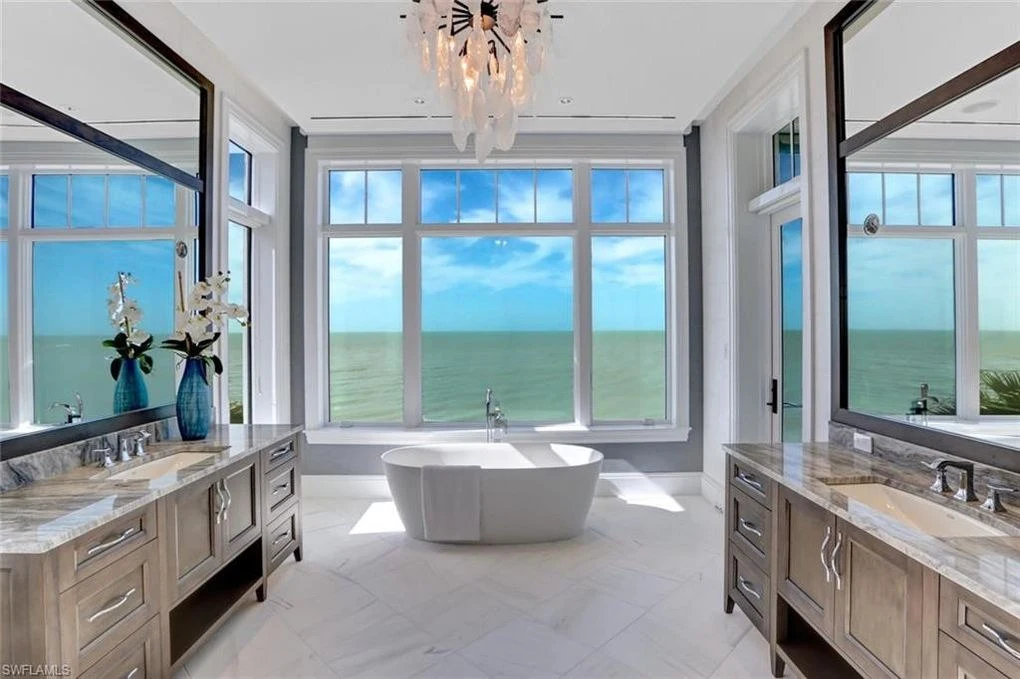 Pale bathroom cabinetry, a freestanding bath, and expansive water views