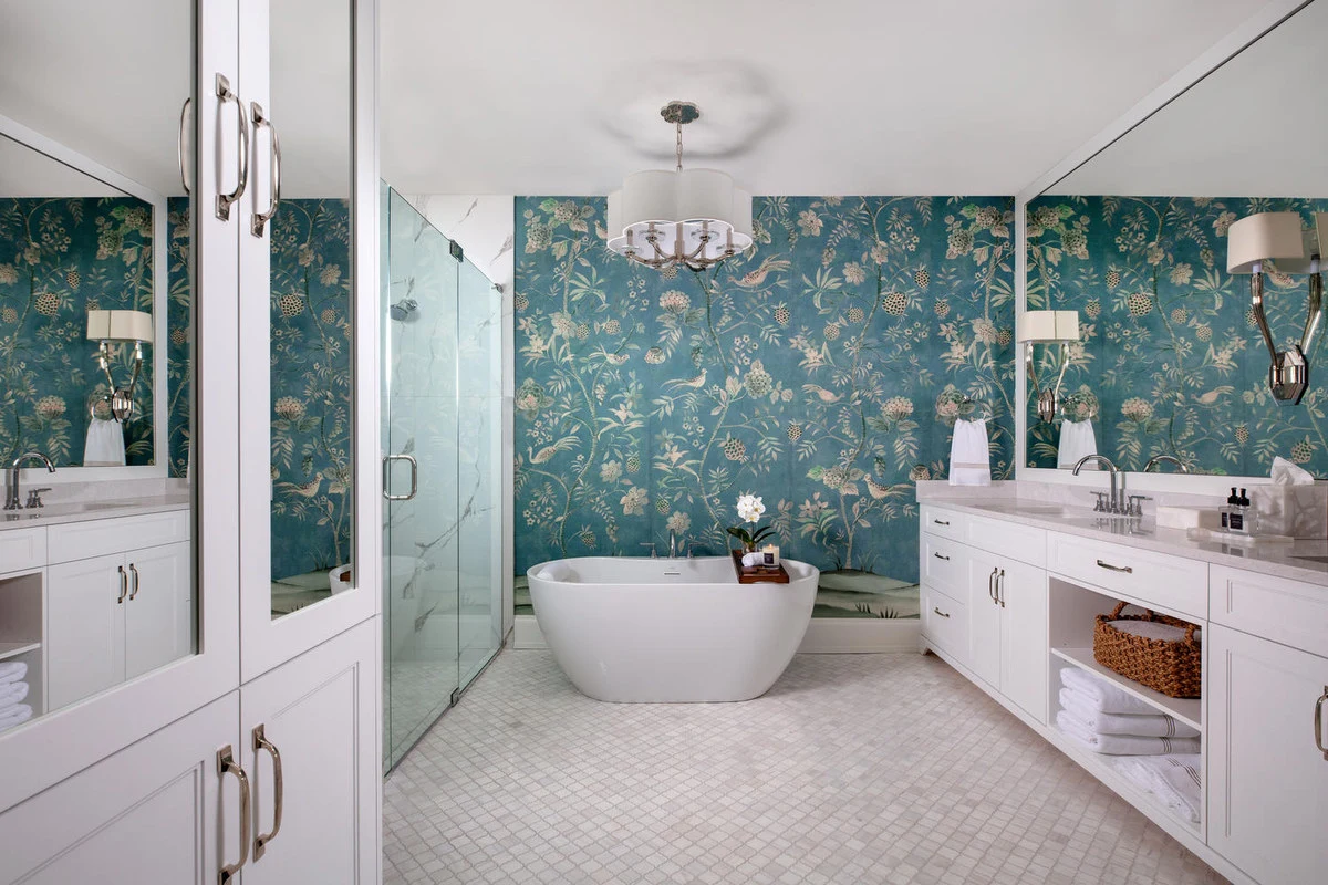White bathroom cabinetry with floral wallpaper and a freestanding bath