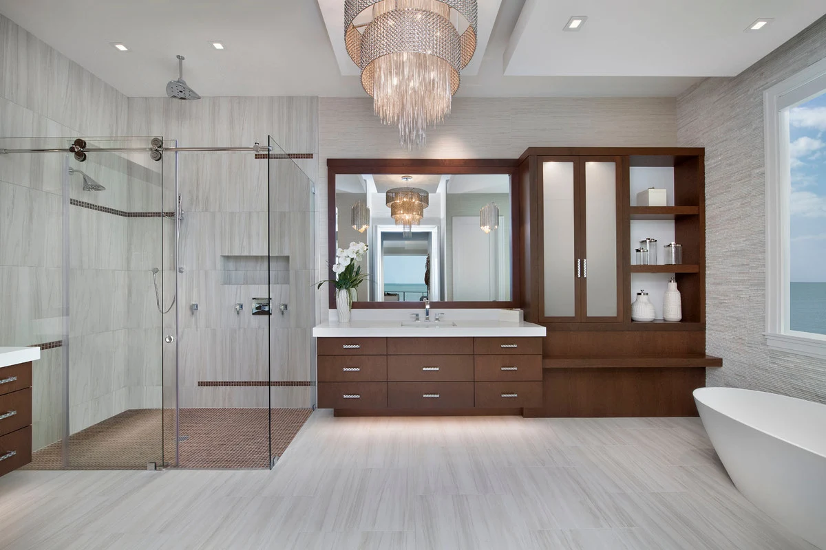 Dark wood bathroom vanity with pale stone surfaces and a central chandelier