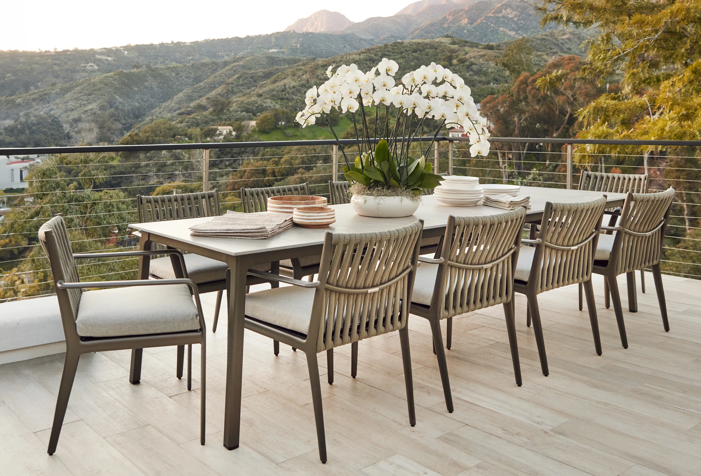 Outdoor dining furniture on a terrace overlooking a green valley