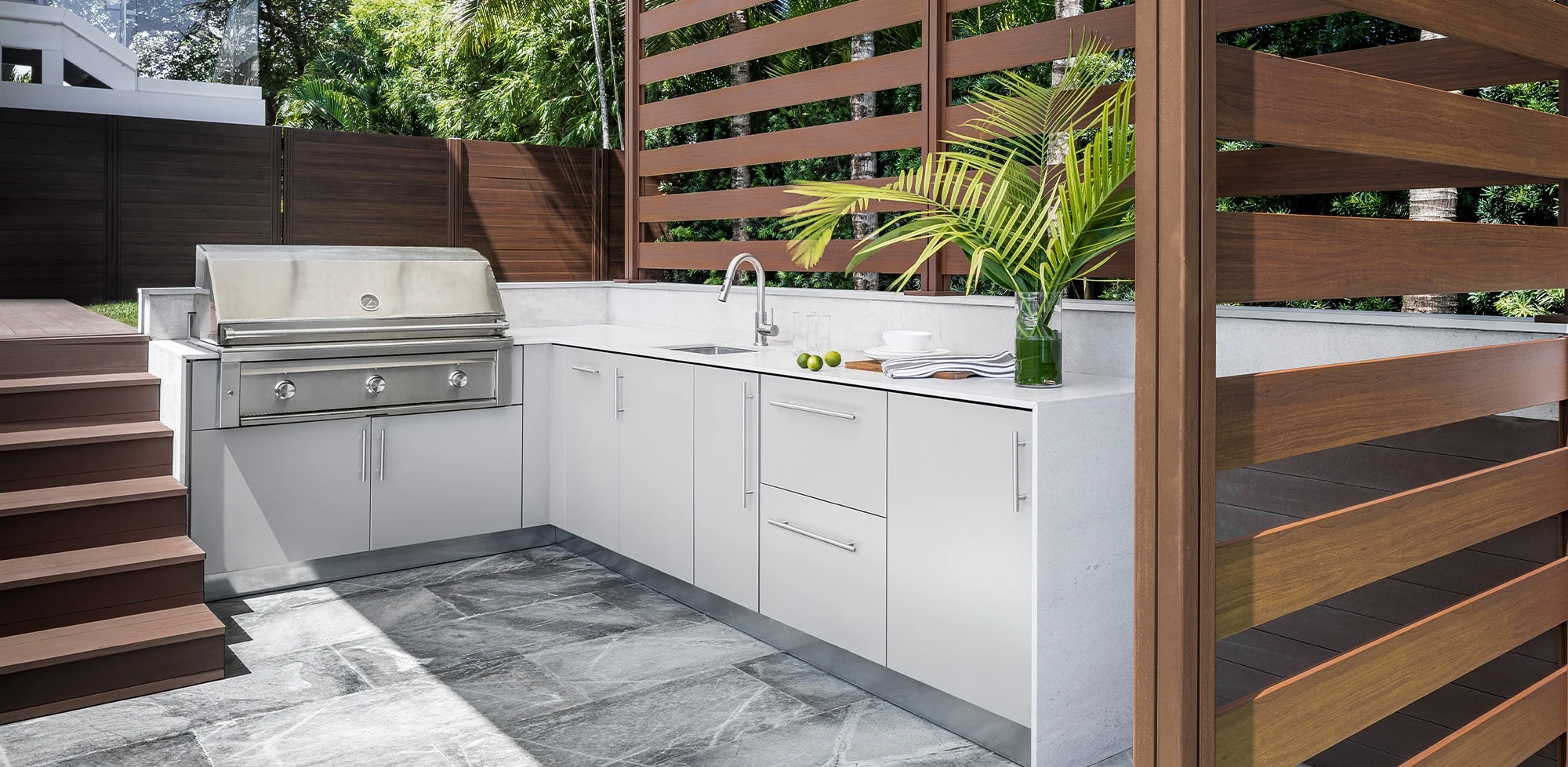 Pale outdoor cabinetry with a stainless grill beneath a canopy and timber screens
