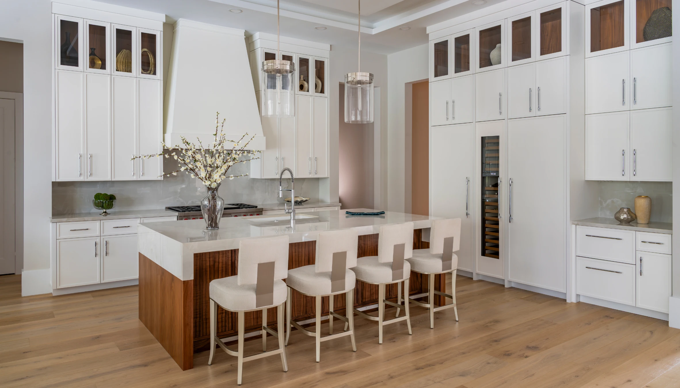 White kitchen cabinetry with a warm wood island and glass display doors