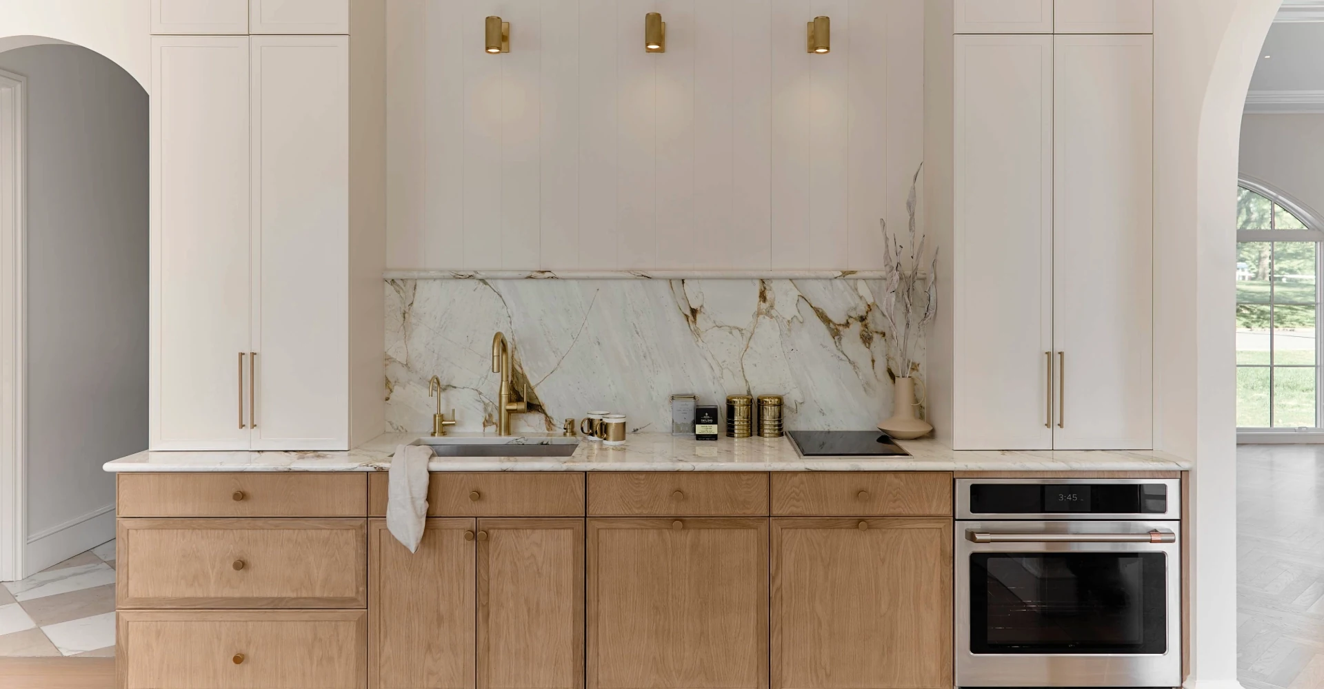 Pale oak kitchen cabinetry with a curved island and arched architectural details