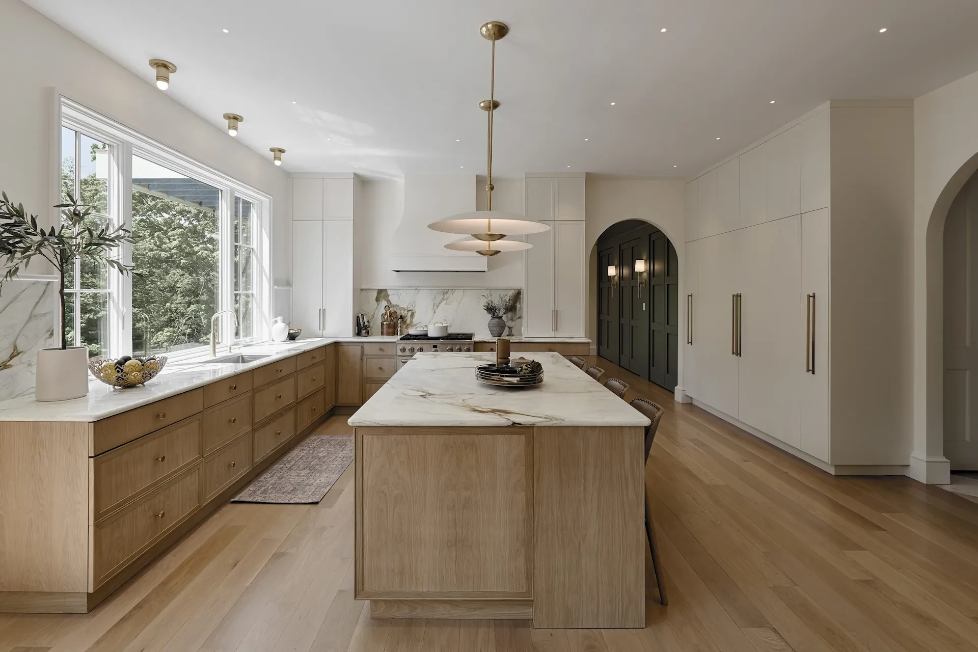 Warm oak island and cabinetry with a long run of garden-facing windows