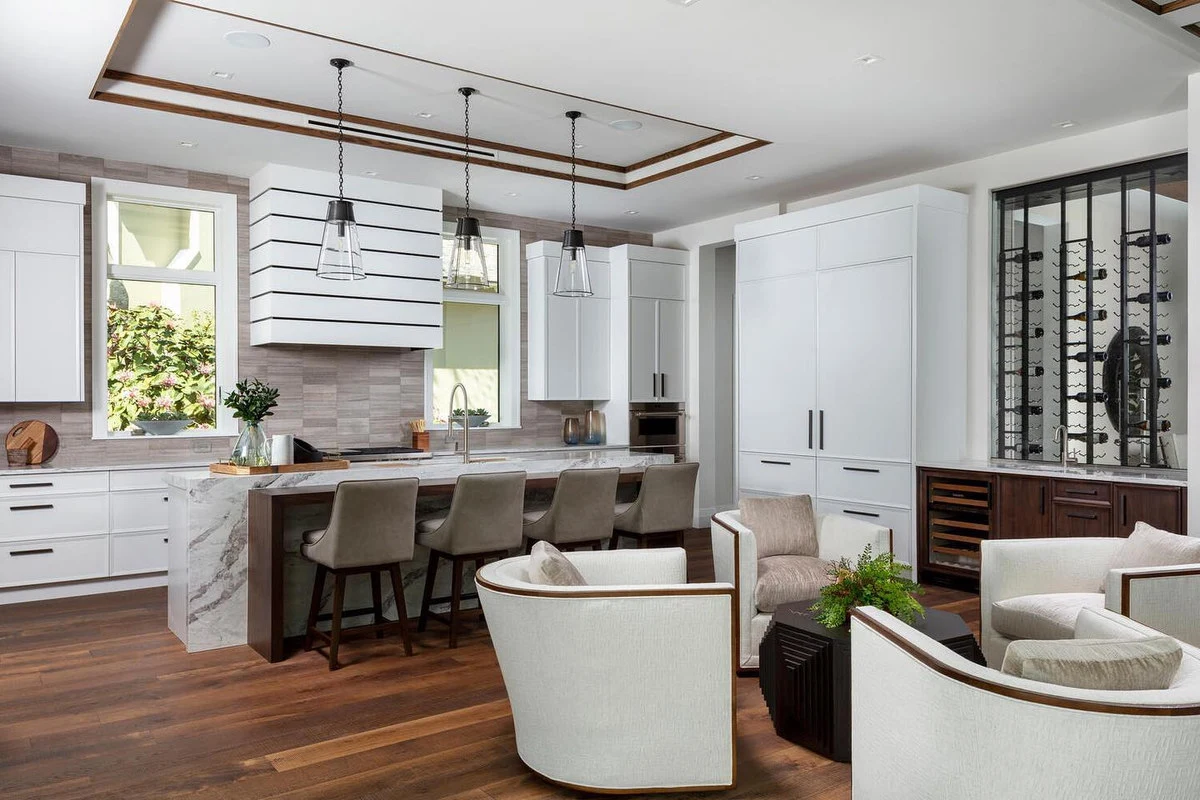 Bright white kitchen cabinetry, a long island, and an adjoining living area