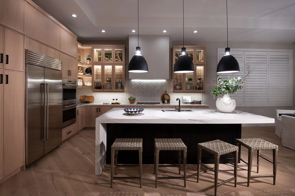 Warm wood kitchen cabinetry with illuminated glass-front cabinets