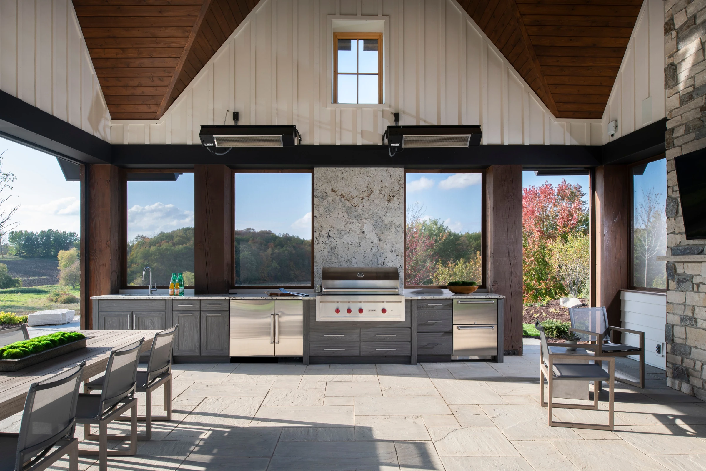 Weathered grey outdoor cabinetry beneath a timber pavilion